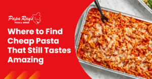 Overhead view of a full aluminum tray of baked penne pasta with marinara sauce and melted cheese, placed on a marble surface.