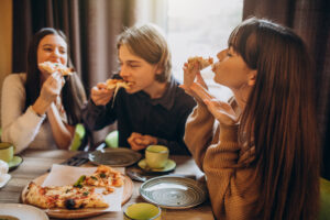 three firends together eating pizza cafe