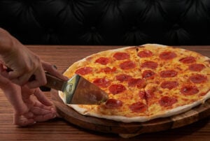 How Many Slices Are in a Large and Regular Pizza? A Simple Guide for Ordering 1 Pepperoni pizza being sliced on a wooden serving board.