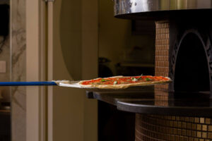 Pizza Restaurants in Carol Stream: What Makes a Great Local Pizza Spot? 2 Fresh pizza being placed into a pizza oven.