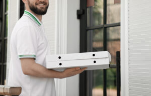 Food Delivery That Accepts Cash: Convenient Meals Without the Hassle 2 Delivery driver handing a pizza box to a customer at the door.